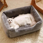Bed for Cats with plush grey fabric and raised cushioned sides featuring a white fluffy cat lying comfortably inside